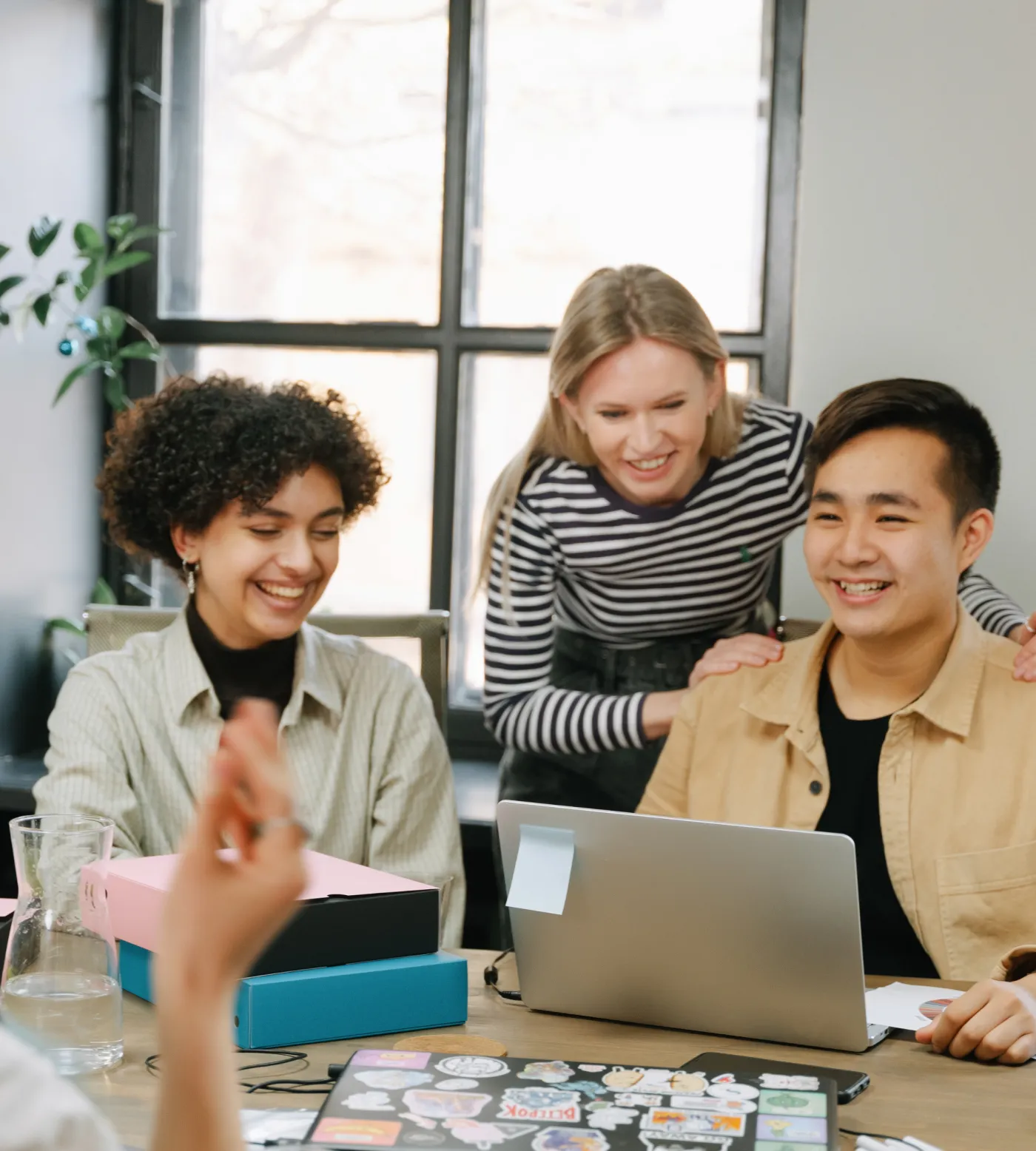 Diverse team of three collaborating around a laptop in a bright office