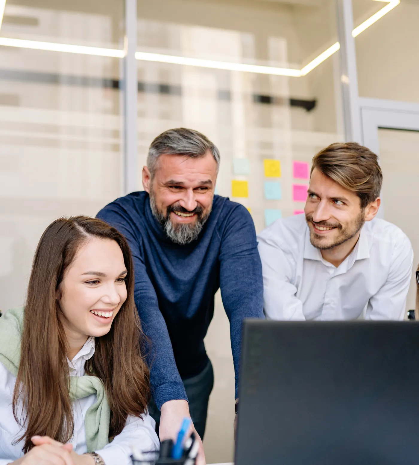 Three colleagues smiling as they review work on a screen together
