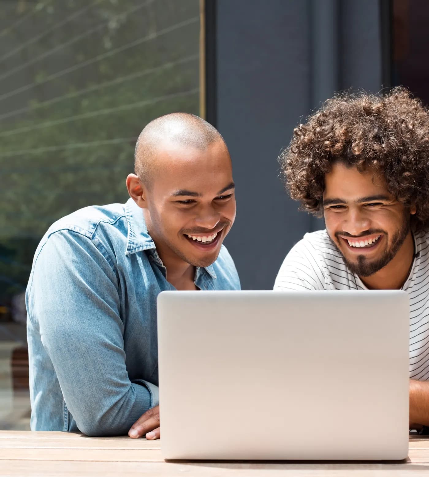 Two builders smiling at a laptop screen together